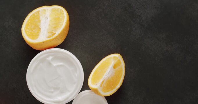 Skin care White Bottle and tubes cream with orange fruit for cosmetics rotating on a black background in studio. Glossy cosmetic jar with cream. Group of different cosmetic bottles. cosmetics product.