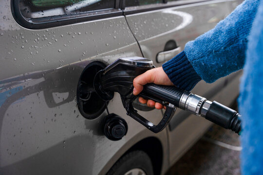 Filling up a car with gas at a station on a rainy day in the morning