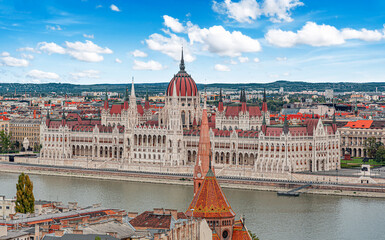 Naklejka premium The Hungarian Parliament Building stands majestically along the banks of the Danube River under a bright blue sky in Budapest.