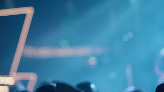 Wide defocused frame showing teal blue concert stage haze, bright bokeh points of light and blurred crowd silhouettes in lower portion