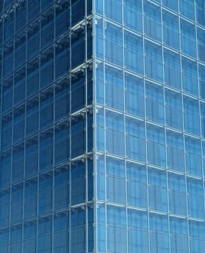 Fondo con vista de cerca de esquina de fachada moderna de edificio de oficinas con paneles de vidrio con marcos met&aacute;licos y reflejos 