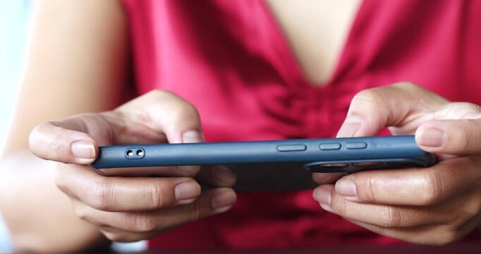 Woman holding smartphone, playing games or typing messages. Everyday mobile use, communication and modern technology concept