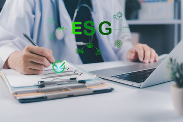 Fototapeta premium AI Healthcare Sustainability. Person in white coat writing on clipboard with ESG icons floating, using laptop for data analysis or reporting.