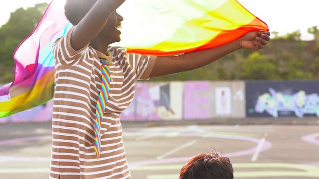 Young multiracial people preparing rainbow flag and celebrating gay pride parade outdoor - LGBT, love and equality concept