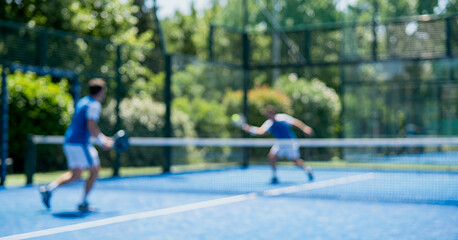 Motion blurred tennis players compete on an outdoor court surrounded by greenery, producing a dreamy and vibrant scene suitable for fitness, recreation, and active lifestyle concepts.