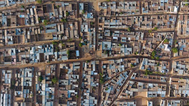 Aerial view of densely packed houses with corrugated metal roofs, narrow dirt roads, and scattered green trees along Steel Rolling Road in Katsina, Katsina, Nigeria.