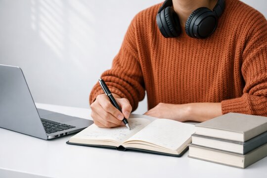 Student writing notes at desk with laptop and books. Ai generati
