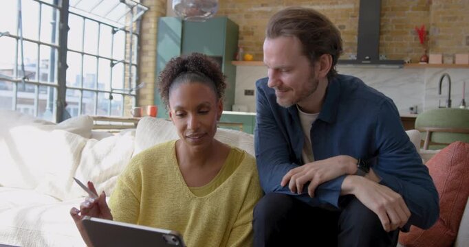 Couple Collaborating Over Digital tablet, Looking at Home Finances