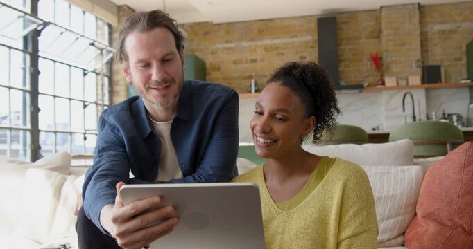 Couple Collaborating Over Digital tablet, Looking at Home Finances