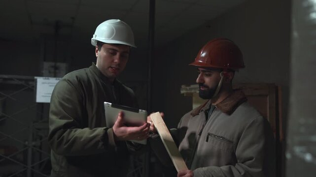 Team Examines Plans And Safety Gear. Warehouse Managers Inspect Blueprints And Enforce Safety Protocols. Media