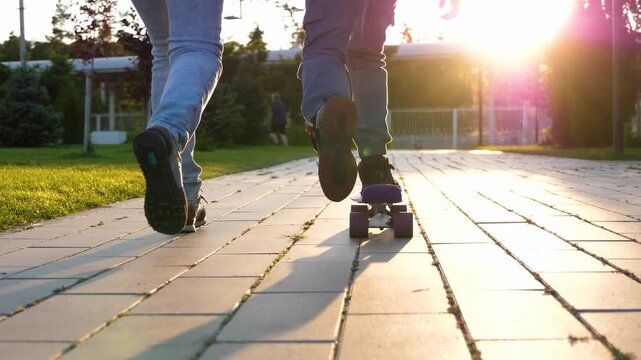 Mother teaching young son to ride skateboard in sunny park. Child learning new skill with support and guidance outdoors. Family bonding and active lifestyle concept. Happy family