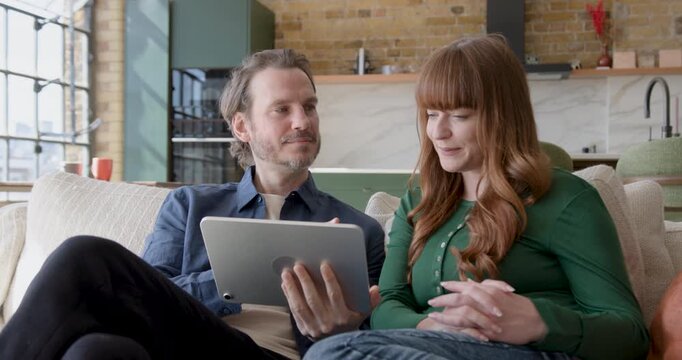 Couple Collaborating Over Digital tablet, Looking at Home Finances
