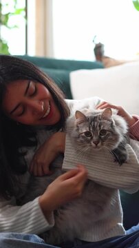 Young women petting a fluffy cat at home