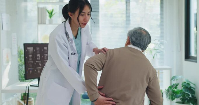 Young Asian female doctor examining senior man with back pain at hospital clinic. Physical therapy treatment, health recovery consult, muscle ache relief, expert physician diagnosis concept.