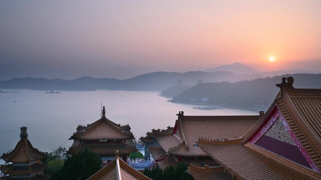 A scenic view of traditional Chinese temple roofs overlooking the calm waters of Sun Moon Lake in Nantou, Taiwan, during a peaceful spring sunset.