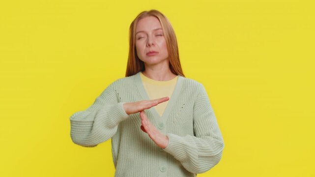 Tired serious upset Caucasian middle-aged woman showing time out gesture, limit or stop sign, no pressure, I need more time, take a break, relax, rest, help. Adult girl isolated on yellow background