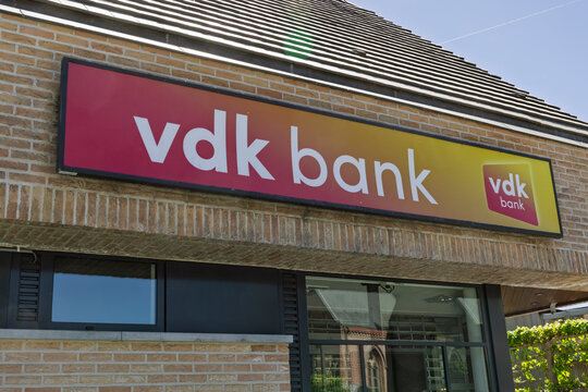 Schelderode, Belgium. May 01, 2026. Close-up view of the modern red and yellow logo sign of VDK Bank on the brick facade of a local branch office.