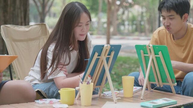 Artistic Inspiration: Young artists, immersed in creative pursuit, find inspiration in the outdoors as they paint, revealing the joy of art in a natural setting.