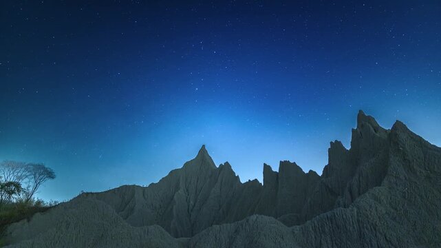 A breathtaking night view of the rugged badlands at Caoshan Moon World in Tainan, Taiwan, illuminated by a vast starry sky during spring.
