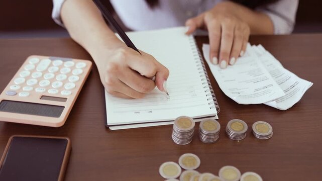 
Smiling woman saves coins into pink piggy bank. Soft light highlights her gentle, joyful expression. Fingers carefully place a coin onto the piggy bank
