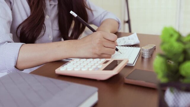 
Smiling woman saves coins into pink piggy bank. Soft light highlights her gentle, joyful expression. Fingers carefully place a coin onto the piggy bank

