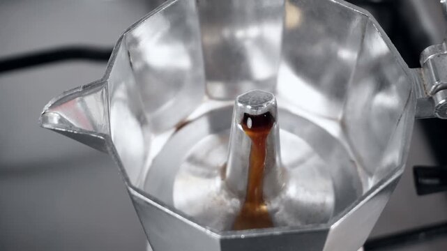 Hot espresso pouring into the upper chamber of an aluminum moka pot