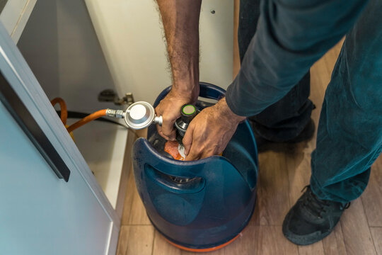 Man, unrecognizable person, changing a gas cylinder in a camper van while traveling.
Transportation, vehicle interior, travel, storage space