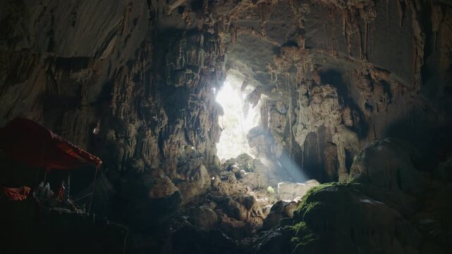 Underground Buddhist temple in large natural limestone cave with a light beam in Laos, Southeast Asia, alternative destination for tourists