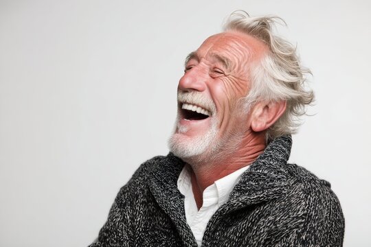 Portrait of a jovial caucasian man in his 60s laughing in front of white background