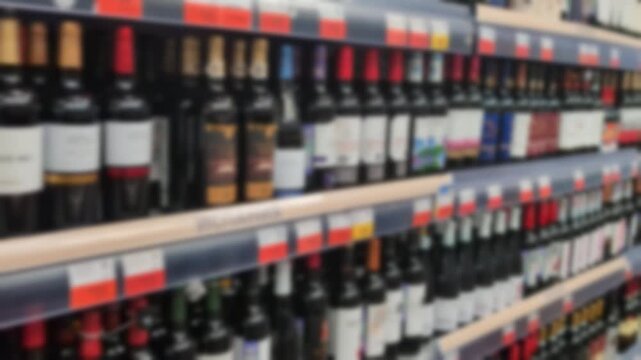 Rows of wine bottles arranged on retail shelves in a liquor or grocery store. Various labels and colors can be seen, indicating a diverse selection of red, white, and ros&eacute; wines.