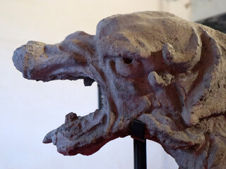 Primo piano di un antico gargoyle in pietra raffigurante una creatura mostruosa con le fauci spalancate in un interno storico © Ilarialapreziosa