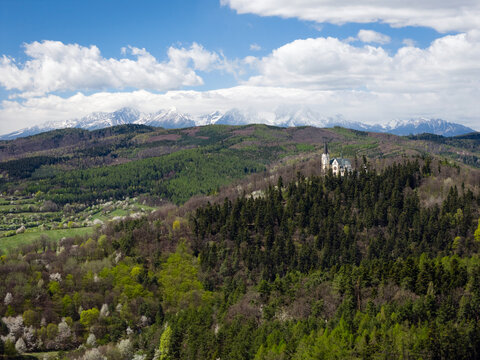 Breathtaking spring view of the Marianska hora pilgrimage site in Levoca, with the snow-capped High Tatras mountains in the background