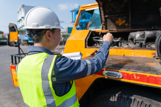 Crane safety inspection engineer mechanic technician hardhat high visibility vest checking engine construction vehicle for preventive maintenance