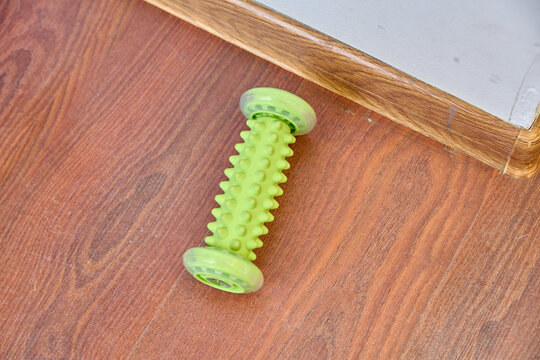 Green textured dog chew toy on wood floor near wall corner