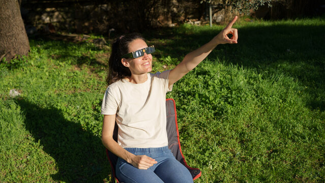 Woman wearing safety glasses observing solar eclipse outdoors