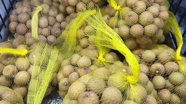  Fresh longan fruit in yellow mesh bags.