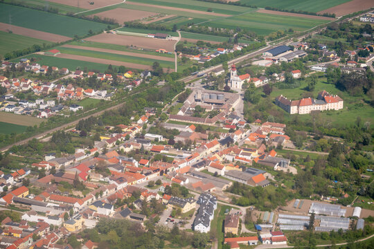 Aerial view of the village center featuring the parish church and Schloss Trautmannsdorf surrounded by green fields in Trautmannsdorf an der Leitha, Niederosterreich, Austria.