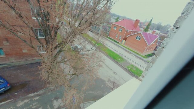 A guy cleans a window outside at the height of the fourth floor. Cleaning of dusty glasses with a plastic sponge. From the first person.