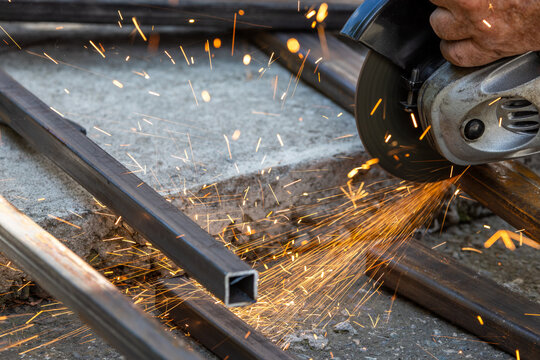 Close-up of angle grinder cutting metal tubing with sparks