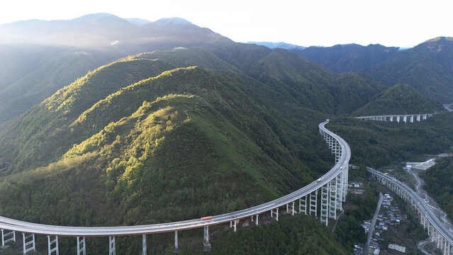 Aerial view of YaXi Highway's iconic double spiral tunnel winding through lush green mountains in Sichuan, China
