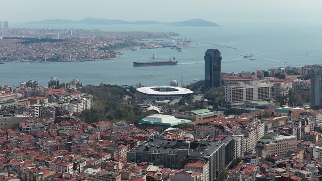 Aerial survey of Istanbul's urban expanse showcasing Bosphorus Strait with cargo ships, historic cityscape, modern architecture, Vodafone Park stadium