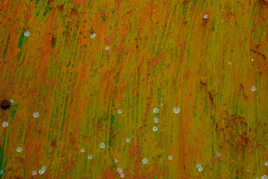 Textured rusty metal surface with green and orange streaks