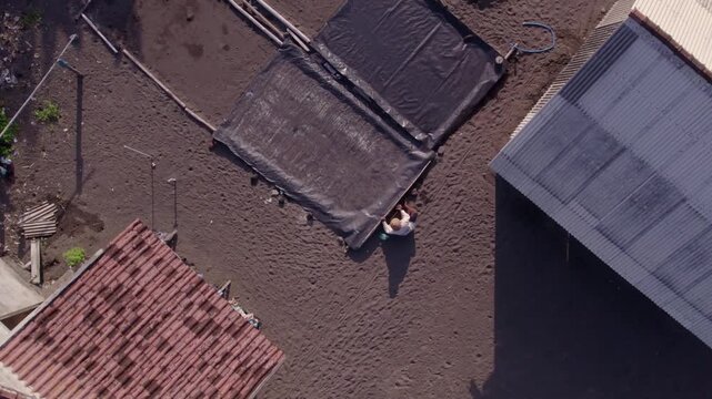 Person working on a muddy field with black tarps