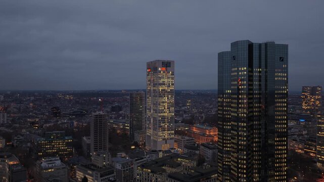 Aerial footage of Frankfurt am Main skyline at twilight, showcasing illuminated skyscrapers including UBS tower Opernturm of financial district