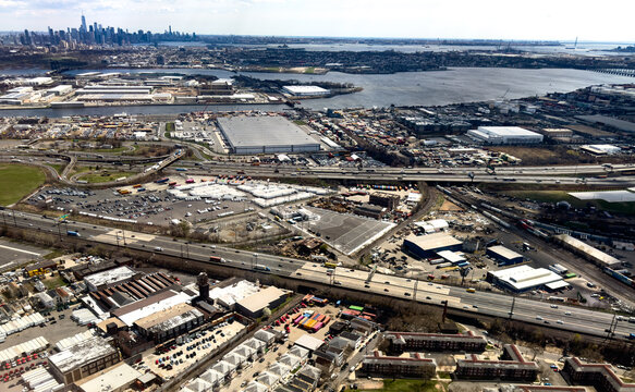 Aerial view of the industrial shipping terminal area with warehouses, busy highways, and the distant New York City skyline in Elizabeth, New Jersey, United States.