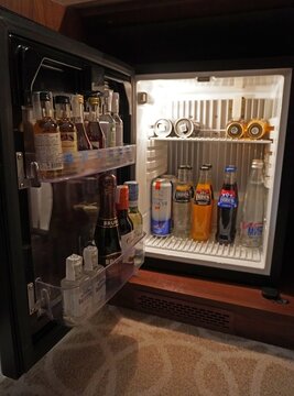 Open hotel mini-bar with drinks and snacks, mini-refrigerator interior in luxury rooms