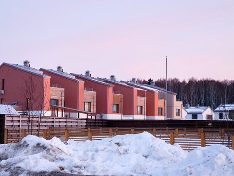 Rows of houses stand in a neighborhood covered with snow. The sky shows signs of sunset