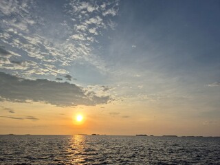 Obraz premium Peaceful ocean sunset with vibrant clouds and serene waves stretching to the horizon, capturing the beauty of nature's tranquility and golden light.