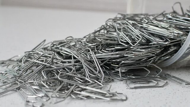 Paper clips intertwined in chaos on a bright surface, a visual representation of disordered creativity.