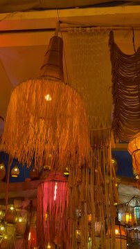 A decorative hanging lamp with fringed fabric in warm tones. The lamp emits a soft glow, creating a cozy atmosphere in a stylish interior setting.